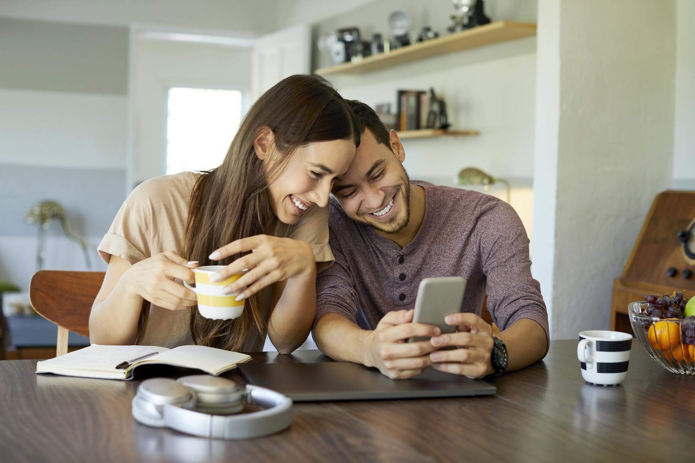 Happy-couple-playing-lottery-online Happy-couple-playing-online-lotto-on-phone-resting-their-heads-on-eachother